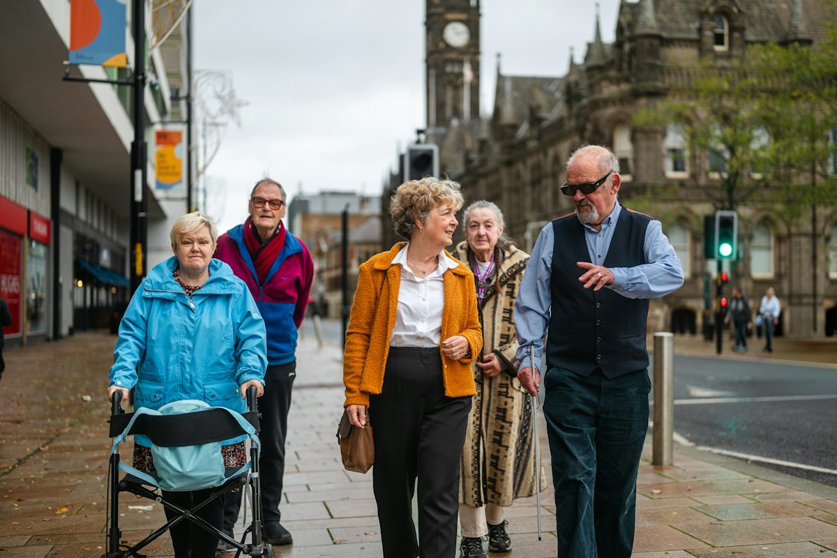 A group of older adults walking together along a city street