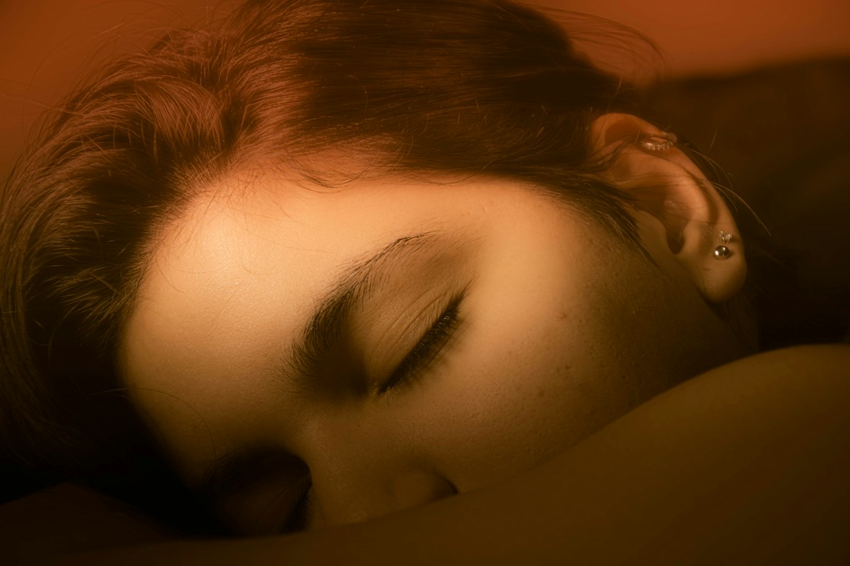 A woman resting with her eyes closed in warm light